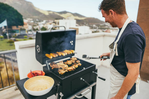 istock Caucasian man grill chicken and corn cobs at home while doing bbq with organic charcoal - Food and summer concept - Soft focus on his ear 1492335328