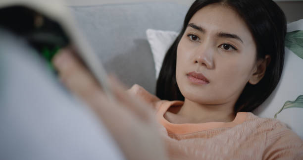 istock Young woman resting to lying on sofa and reading book 1492339304