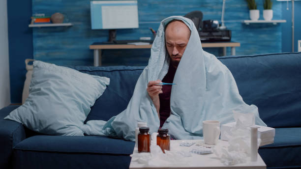 istock Ill man in blanket measuring temperature with thermometer 1492341671