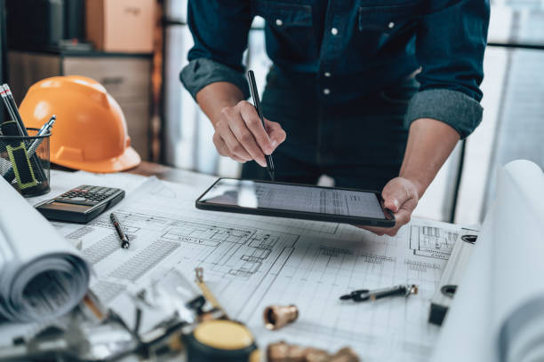 istock Engineering working with drawings inspection on tablet in the office and Calculator, triangle ruler, safety glasses, compass, vernier caliper on Blueprint. Engineer, Architect, Industry and factory concept. 1492342054