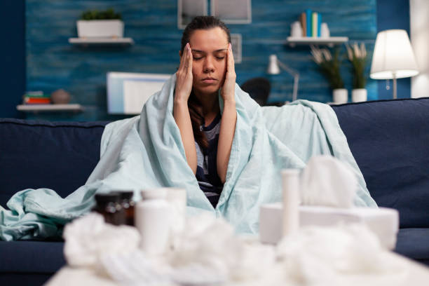 istock Sick woman with headache sitting on sofa at home 1492343217