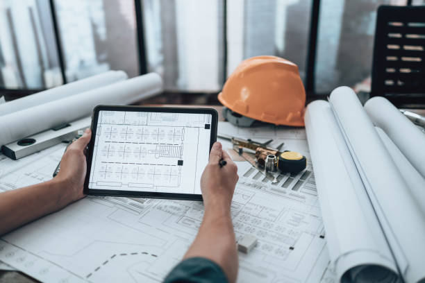 istock Engineering working with drawings inspection on tablet in the office and Calculator, triangle ruler, safety glasses, compass, vernier caliper on Blueprint. Engineer, Architect, Industry and factory concept. 1492343279