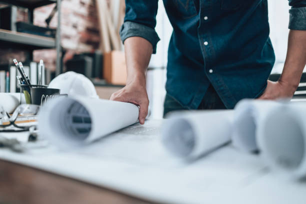 istock Engineering working with drawings inspection on the office desk and Calculator, triangle ruler, safety glasses, compass, vernier caliper on Blueprint. Engineer, Architect, Industry and factory concept. 1492343603