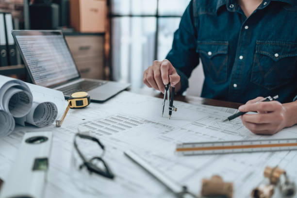 istock Engineering working with drawings inspection and writing on the office desk and Calculator, triangle ruler, safety glasses, compass, vernier caliper on Blueprint. Engineer, Architect, Industry and factory concept. 1492343769