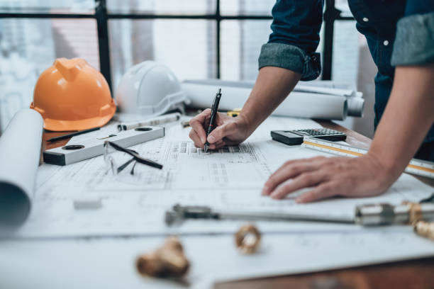 istock Engineering working with drawings inspection and writing on the office desk and Calculator, triangle ruler, safety glasses, compass, vernier caliper on Blueprint. Engineer, Architect, Industry and factory concept. 1492344009