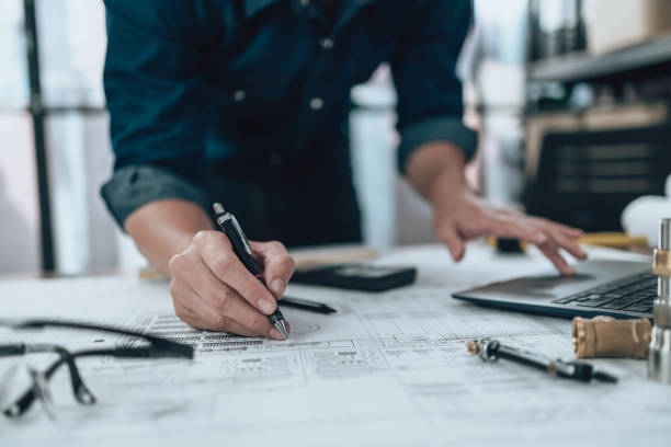 istock Engineering working with drawings inspection and writing on the office desk and Calculator, triangle ruler, safety glasses, compass, vernier caliper on Blueprint. Engineer, Architect, Industry and factory concept. 1492344203