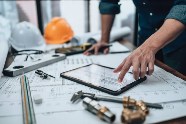 istock Engineering working with drawings inspection on tablet in the office and Calculator, triangle ruler, safety glasses, compass, vernier caliper on Blueprint. Engineer, Architect, Industry and factory concept. 1492344237