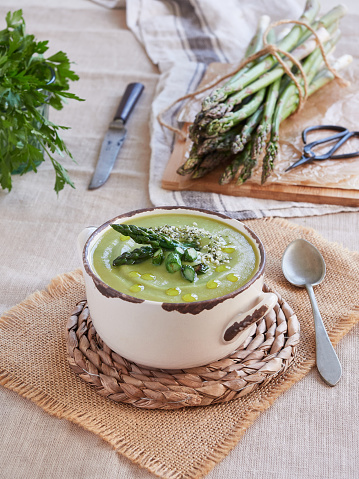 bowl of creamy green asparagus soup with green wild asparagus tips and olive oil on top
