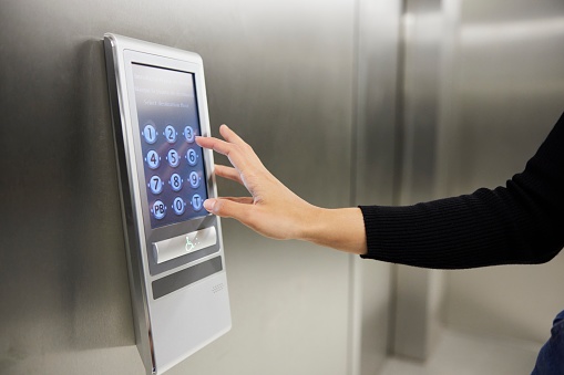 A hand psuhing elevator buttons in a digital display.