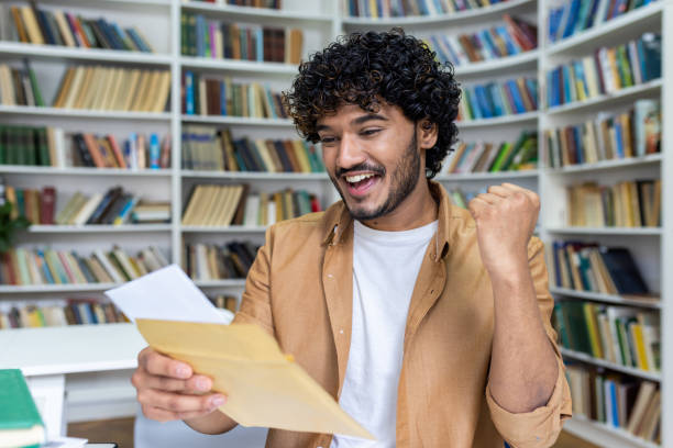 istock Young student received letter with good exam results and university admission confirmation, hispanic man with curly hair celebrating successful achievement holding hand up close up 1492356452