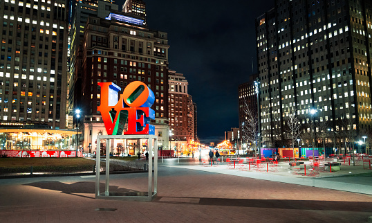 Philadelphia, USA - People in the background in Love Park at night in downtown Philadelphia, with the reproduction of the LOVE sculpture illuminated.