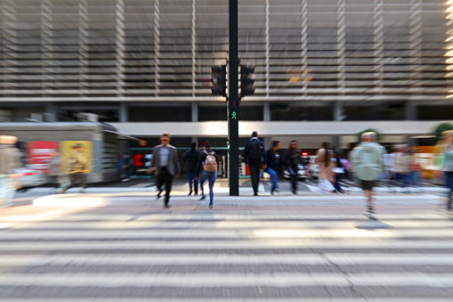 People crossing an avenue at the crosswalk, in a big city, with blurred effect (zooming).