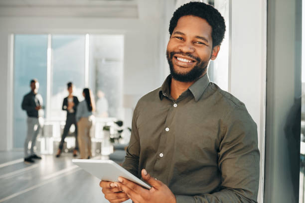 Portrait, digital tablet and black man in office happy, smile and empowered, ambition and mindset. Face and business man or ceo at startup company for management or online project at workplace stock photo