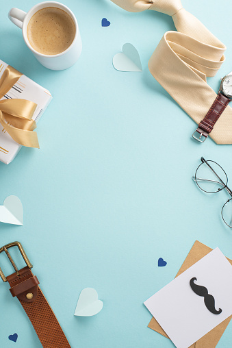 Top vertical view layout. Create a sophisticated Father's Day with tie, clock, glasses, belt, giftbox, envelope with postcard, coffee cup, hearts, on blue background with an empty frame for advert