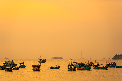 Beautiful cloudscape over the sea, sunrise shot.Many boats. Vung Tau beach, Vietnam with beautiful yellow sunrise sky, sun and clouds in orange and blue tones. Background and travel concept.