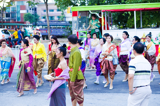 Group of traditional dressed thai women and men is arriving at event in Phitsanulok. It is a public free local traditional culture event organized by local government. History week in Phitsanulok with traditional food, clothings and performances about history. Event  takes place at historical grounds of Wat Wihan Thong Historical Site near Nan river and is local way of keeping history alive. People are coming by old vintage  bus