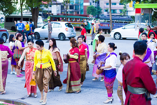 Capture of medium group of traditional dressed thai women and men is arriving at event in Phitsanulok. It is a public free local traditional culture event organized by local government. History week in Phitsanulok with traditional food, clothings and performances about history. Event  takes place at historical grounds of Wat Wihan Thong Historical Site near Nan river and is local way of keeping history alive. People are coming by old vintage  bus