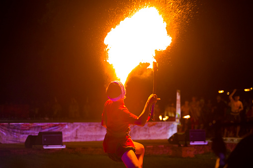 Thai fire-eater at Traditional thai festival in Phitsanulok in midnorthern Thailand. Man is part of group of performing fire-eating at night during public free local traditional culture event organized by local government. History week in Phitsanulok with traditional food, clothings and performances about history and battles with Myanmar. Performance takes place at historical grounds of Wat Wihan Thong Historical Site near Nan river and is local way of keeping history alive