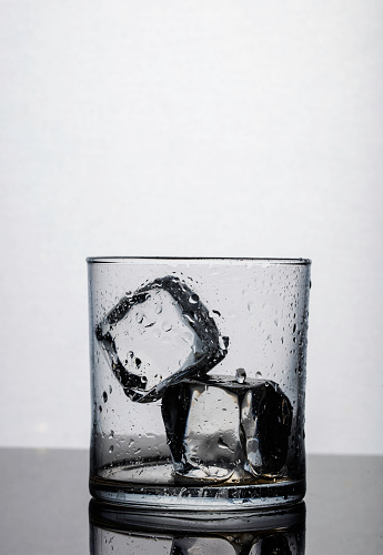 Drinking glass with two ice cubes and water drops