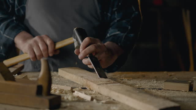 Sawmill, Middle-aged builder Works with a chisel knocking chips out of wood Working with tools
