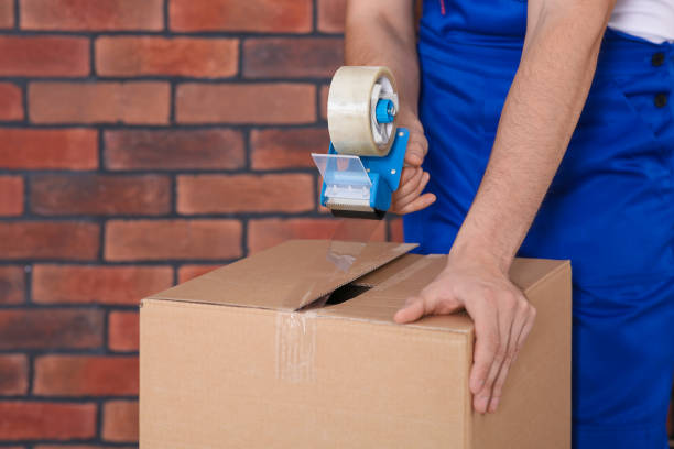 istock Worker taping box with adhesive tape dispenser near brick wall, closeup 1492372091