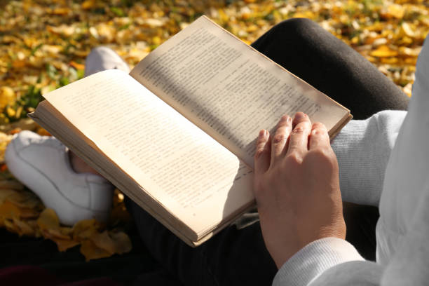 istock Woman reading book outdoors on autumn day, closeup 1492372156