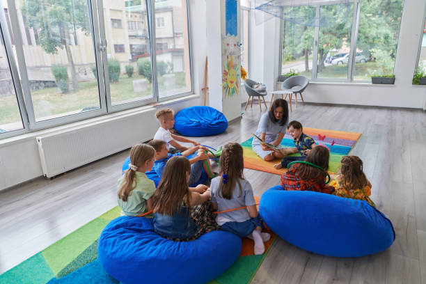 istock Reading time in an elementary school or kindergarten, a teacher reading a book to children in an elementary school or kindergarten. The concept of pre-school education. Selective focus 1492373864