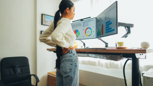 istock Woman with back pain working at standing desk home office 1492373912