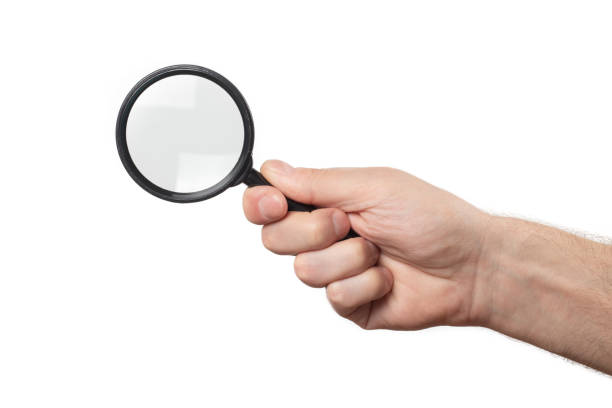 istock Man's hand, holding classic styled magnifying glass, closeup isolated on white background 1492374162
