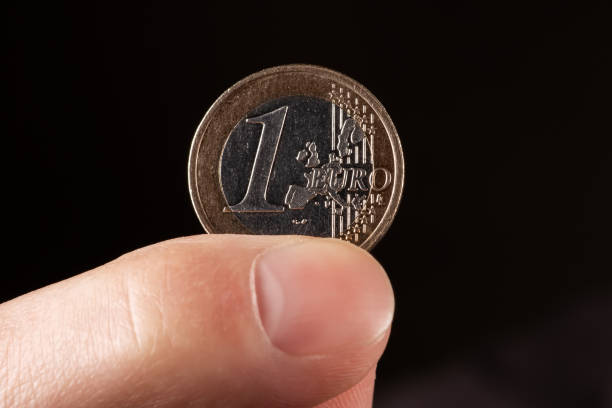 istock A hand holding one euro coin on black background 1492374293