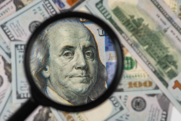 istock Magnifying glass on 100 dollar banknotes close up 1492374328