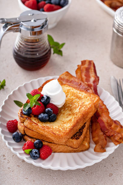 Classic french toast with bacon and berries Classic french toast with bacon and fresh berries topped with whipped cream french toast bacon bread butter stock pictures, royalty-free photos & images