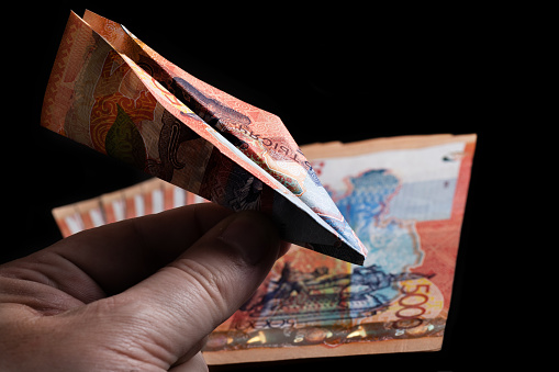 A miniature plane made from a 5000 tenge banknote in a man's hand