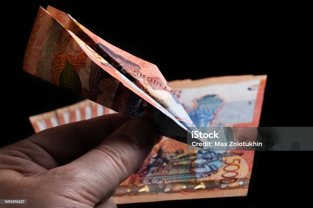 A miniature plane made from a 5000 tenge banknote in a man's hand Aerospace Industry Stock Photo