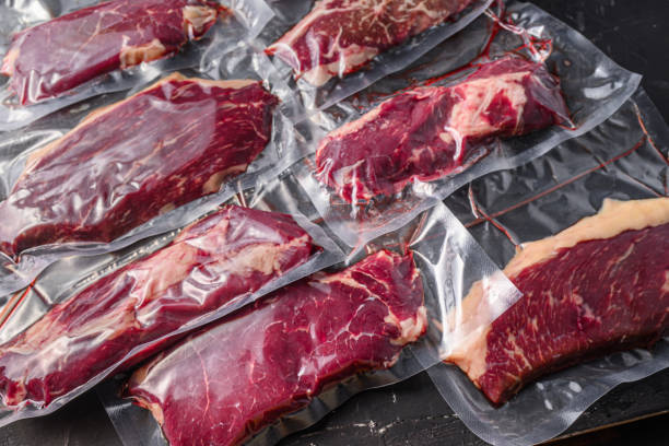 istock Vacuum packed organic raw beef alternative cuts: top blade, rump, picanha, chuck roll steaks, over black textured background, side view. 1492376910