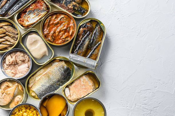 istock Tin cans for processed  food  cans conserve Saury, mackerel, sprats, sardines, pilchard, squid, tuna pinapple, corn, peas, mango ,  beans,   over white textured background overhead view space for text 1492377045