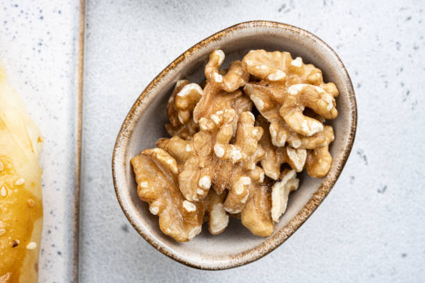 istock Nuts in bowl, on white stone table background, top view flat lay 1492377094
