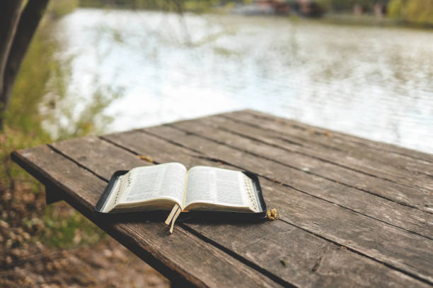 istock Open Bible on a wooden board near the river 1492378409
