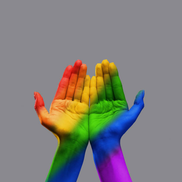 istock Human hands with open palms and rainbow lights on it over grey background. Lgbt community support, acceptance 1492379059