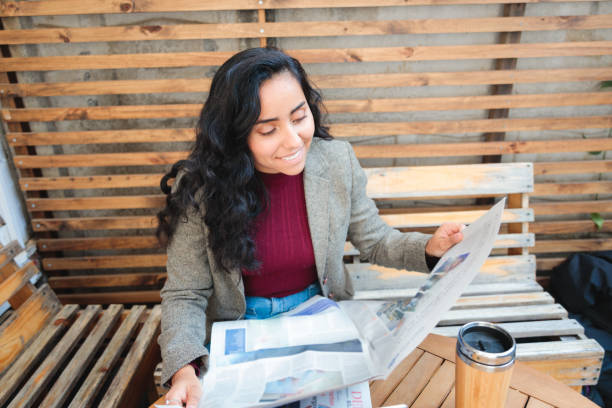 스타일리시한 구직 활동: 아늑한 카페에서 신문으로 일자리를 찾는 젊은 라틴계 여성 - job search newspaper coffee shop cafe 뉴스 사진 이미지
