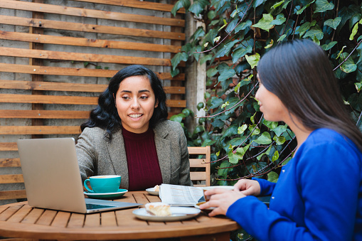 Secure Your Future: Latina Insurance Saleswoman Presenting Life Insurance Options to a Customer in a Cafe