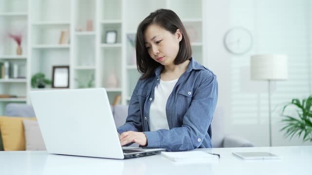 Adult asian businesswoman typing on laptop while sitting in home office