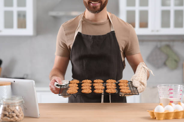 istock Man holding grid with freshly baked cookies in kitchen, closeup. Online cooking course 1492387642