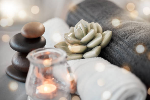 rock, candela e asciugamano in una spa per lo zen per rilassarsi in una stanza vuota senza stress con atmosfera aromaterapica. lusso, salone e benessere con oggetti still life in un interno per rilassanti sollievo dallo stress - spa treatment health spa wellbeing lastone therapy foto e immagini stock