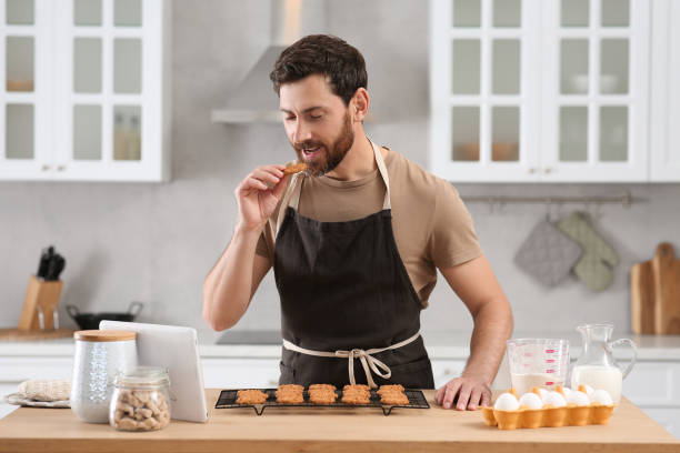 istock Man with freshly baked cookies watching online cooking course via tablet in kitchen 1492387958