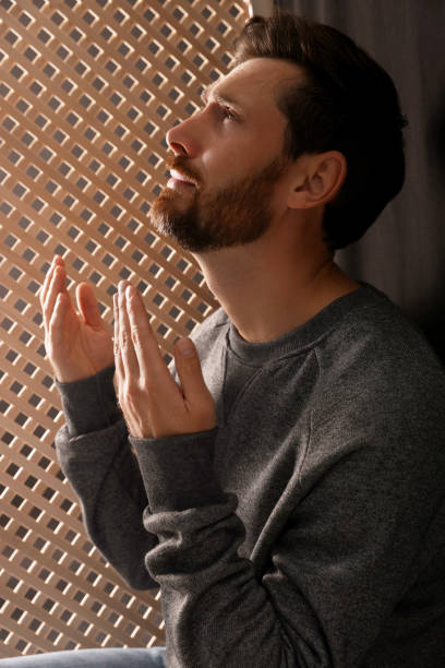 ブースでの告白中に神に祈る男 - confession booth ストックフォトと画像