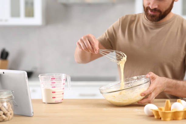 istock Man making dough while watching online cooking course via tablet in kitchen, closeup 1492388114