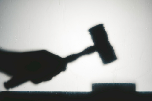 Silhouette view of hand with gavel. Representing justice system.