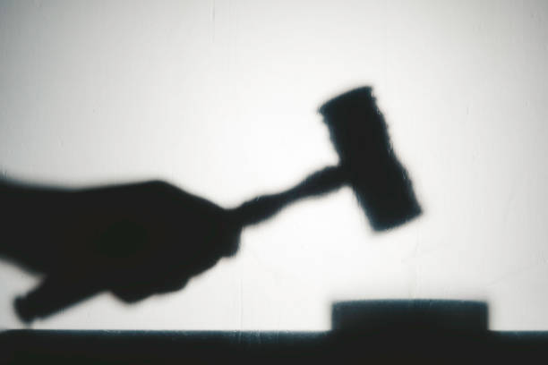 Justice System Silhouette view of hand with gavel. Representing justice system. judgement stock pictures, royalty-free photos & images