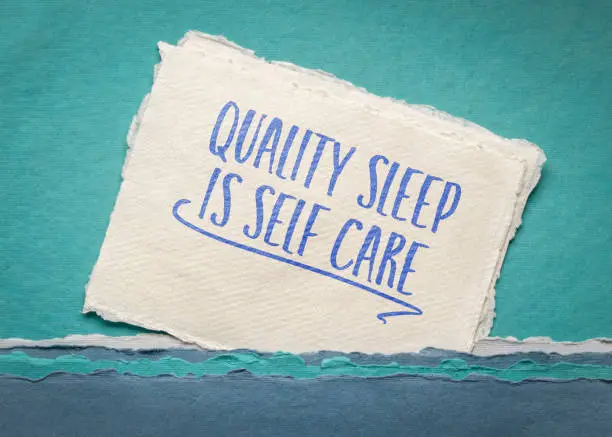 Photo of quality sleep is self care - inspirational reminder note on an art paper, healthy lifestyle concept